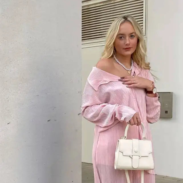 Woman in pink pleated outfit with white handbag showcasing texture loose casual style