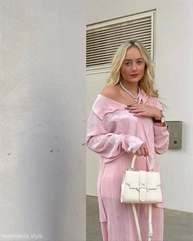 Woman in pink pleated outfit with white handbag showcasing texture loose casual style