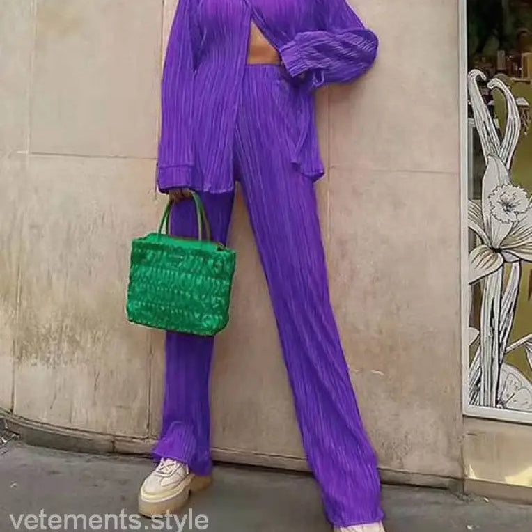 Purple pleated pantsuit with green handbag showcasing casual polyester texture and style