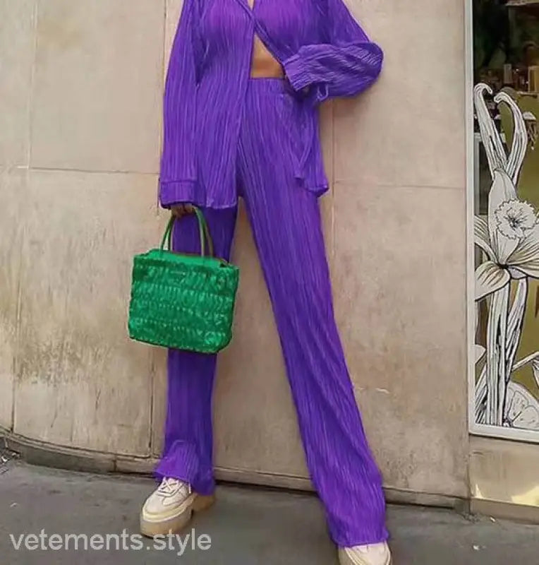 Purple pleated pantsuit with green handbag showcasing casual polyester texture and style
