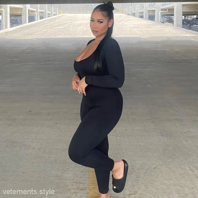 Woman in a sexy soft jumpsuit posing in a parking structure, showcasing light gray style