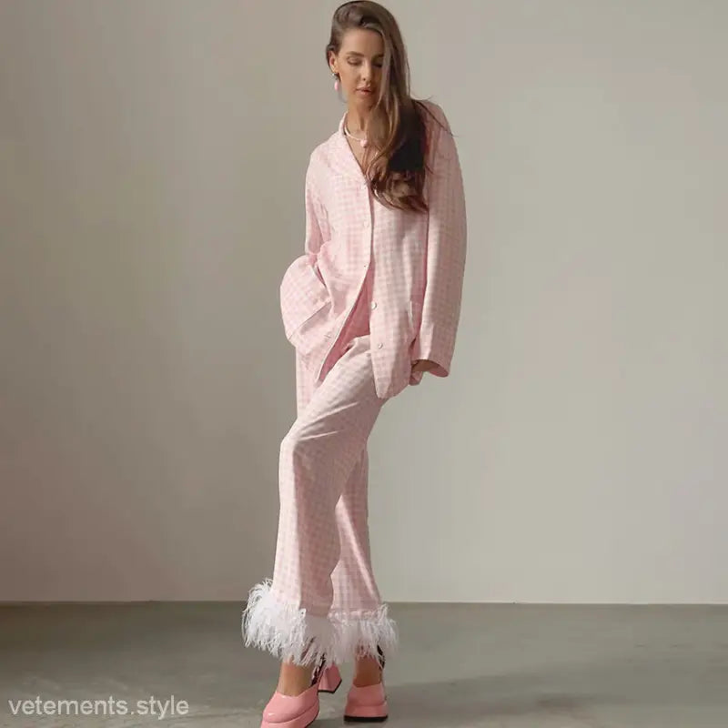 Woman in pink loose satin pajamas two piece with feather-trimmed pants and slippers