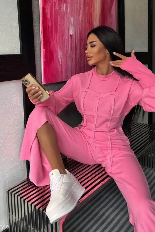 Woman in vibrant pink modern hoodie set with long sleeve and full-length pants posing with drink