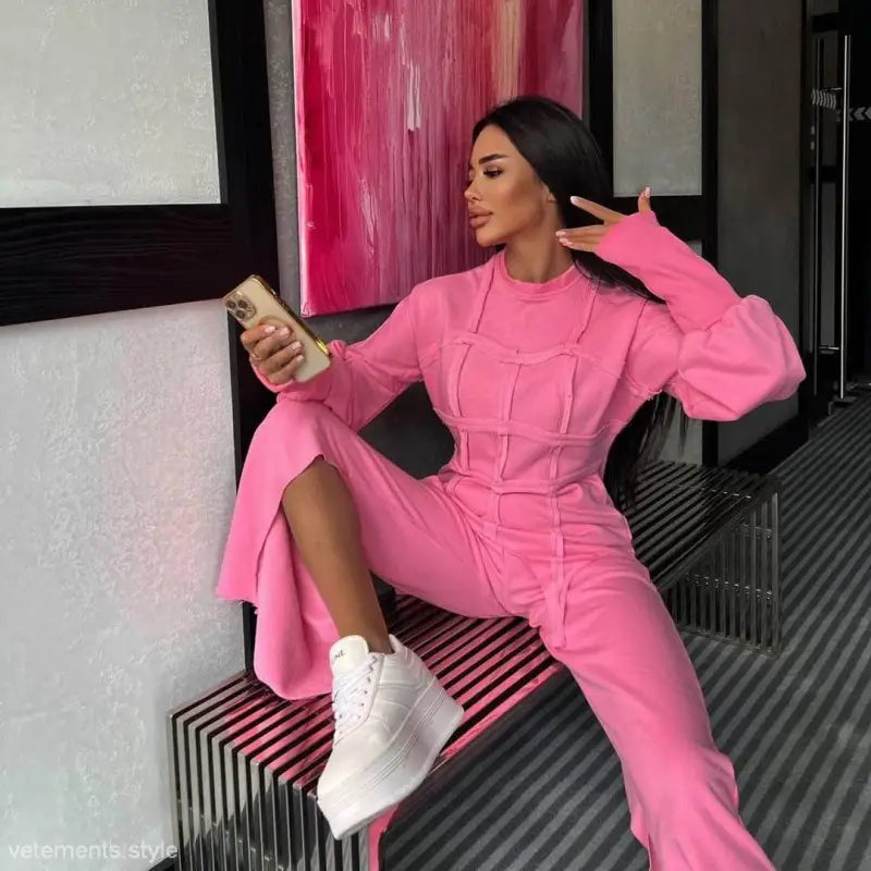 Woman in vibrant pink modern hoodie set with long sleeve and full-length pants posing with drink