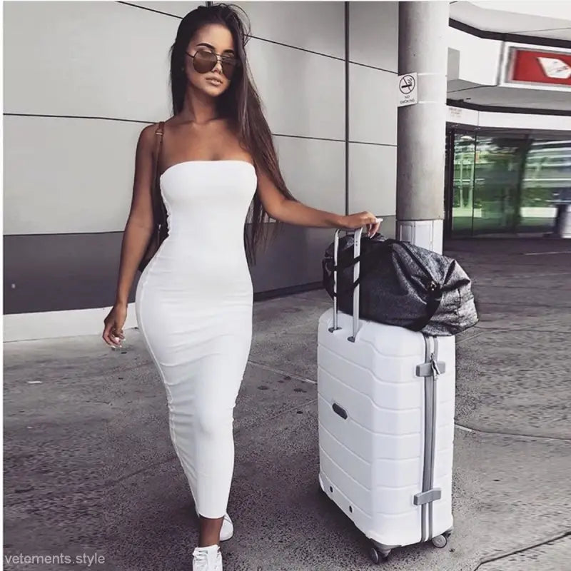 Woman in a white dress with suitcase showcasing navy blue bodycon midi dress for summer fashion