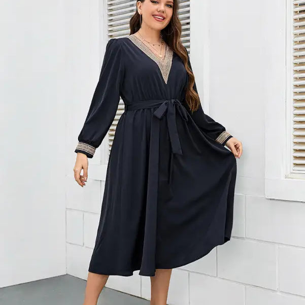 Navy blue wrap dress with long sleeves and gold trim detailing.