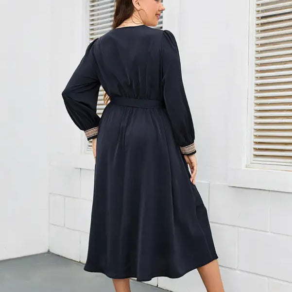 Navy blue long-sleeved midi dress with embellished cuffs and a cinched waist.