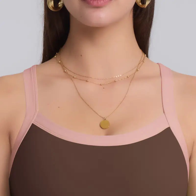 Woman’s gold layered necklace paired with navy blue strength yoga bra for all seasons