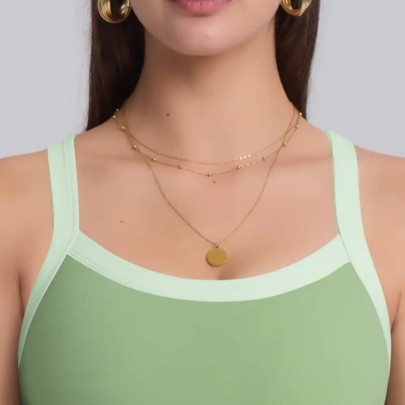 Woman’s gold layered necklace styled with Navy Blue Sporty Slim Nylon Strength Yoga Bra for All Seasons