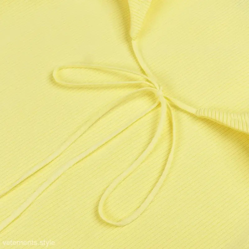 Close-up of pale yellow lace backless bodycon midi dress with tie-front detail