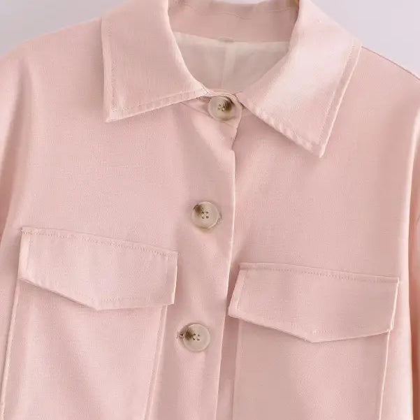 Pale pink button-up shirt with chest pockets hanging on wooden hanger for Pink Pants and Top Blazer High