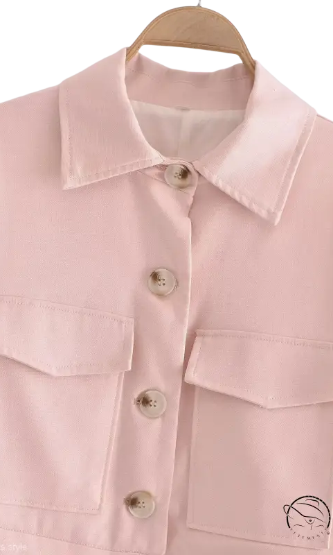 Pale pink button-up shirt with chest pockets hanging on wooden hanger for Pink Pants and Top Blazer High