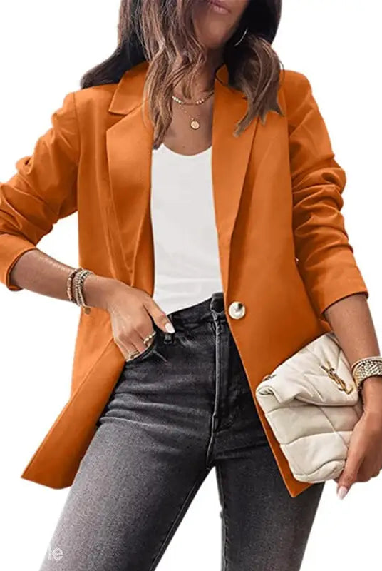 Woman wearing a purplish blue slim fit jacket with jeans and a clutch for office style