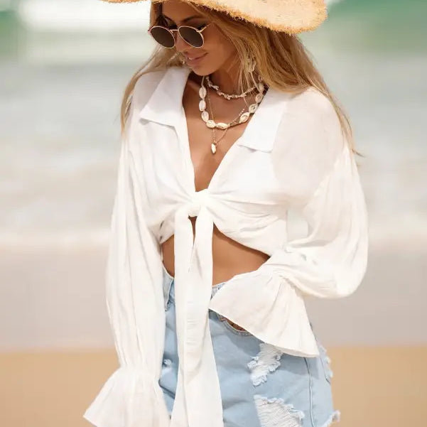 Woman in beach attire wearing a Royal Blue Boho Tie Sleeve Top ideal for summer vacation