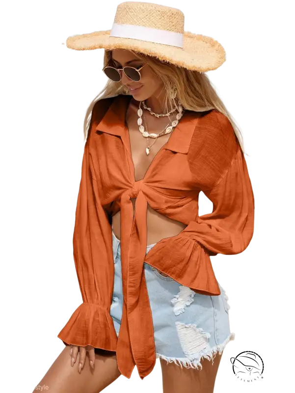 Woman in royal blue boho tie-sleeve top, denim shorts, straw hat