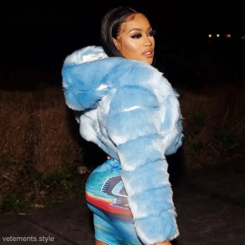 Woman in royal blue faux fur coat posing outdoors at night