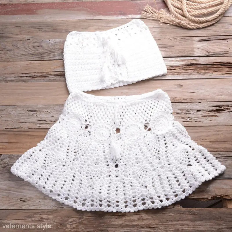 White crocheted two-piece outfit featuring intricate lace, shoulder bikini straps, and flared skirt