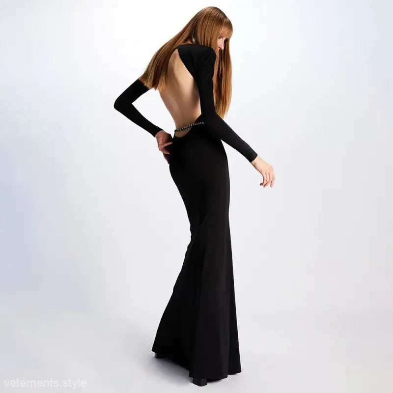 Long black backless maxi dress with mermaid silhouette modeled by a woman with straight hair