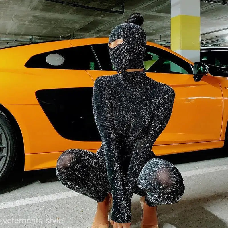 Person wearing a sexy Catwoman jumpsuit with cutout design in front of an orange sports car