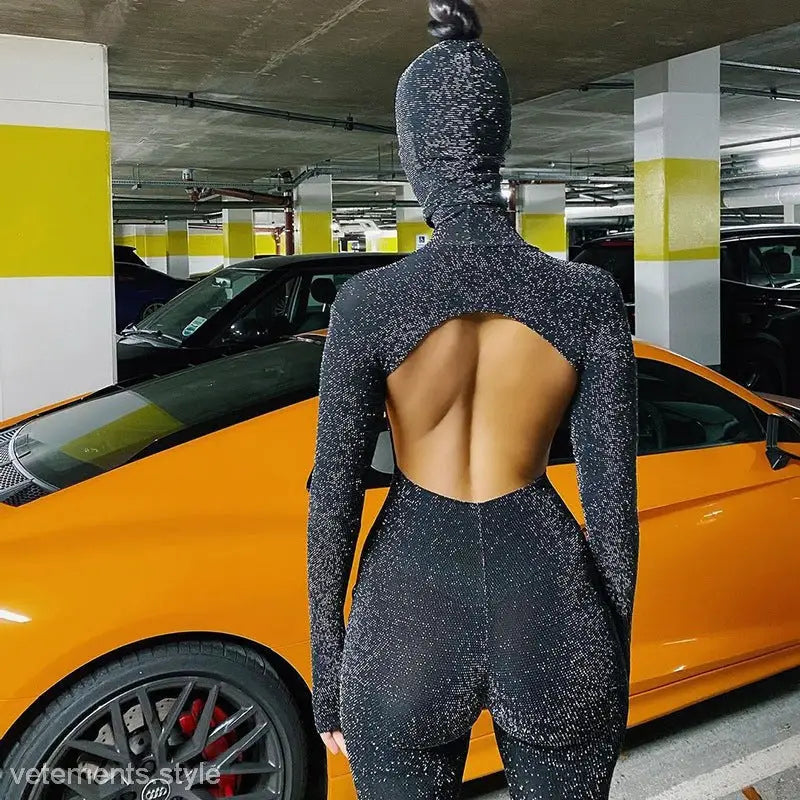 Sexy Catwoman jumpsuit with open back, black glitter fabric, next to an orange sports car