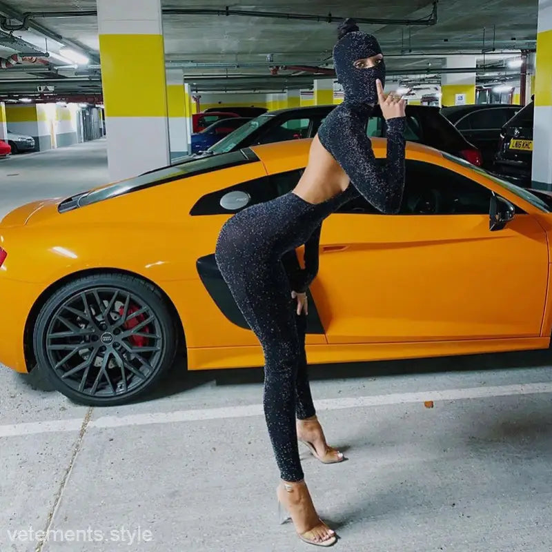 Yellow sports car with person in sexy Catwoman jumpsuit posing in parking garage