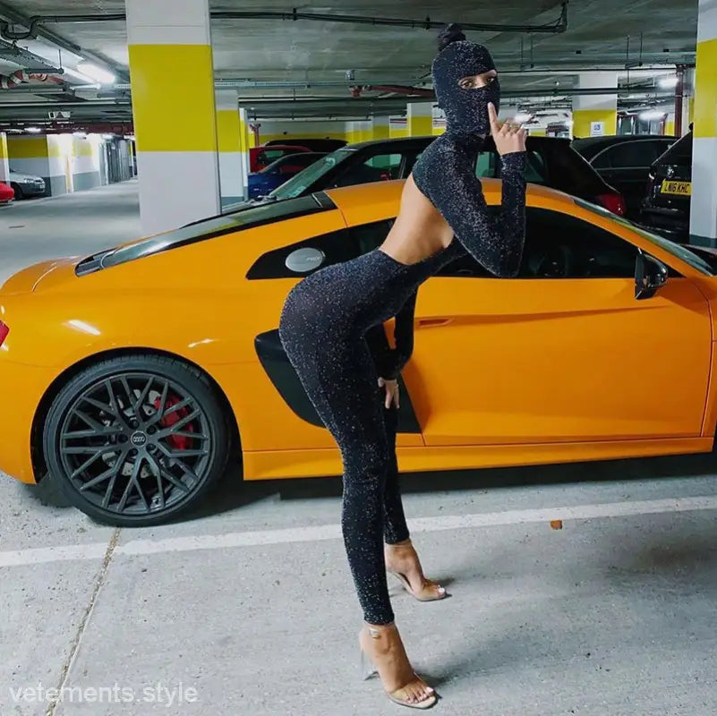 Yellow sports car with person in sexy Catwoman jumpsuit posing in parking garage