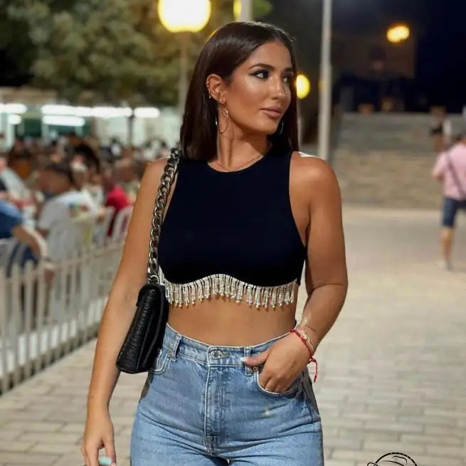 Woman in sexy daily vest: black fringe crop top with high-waisted jeans