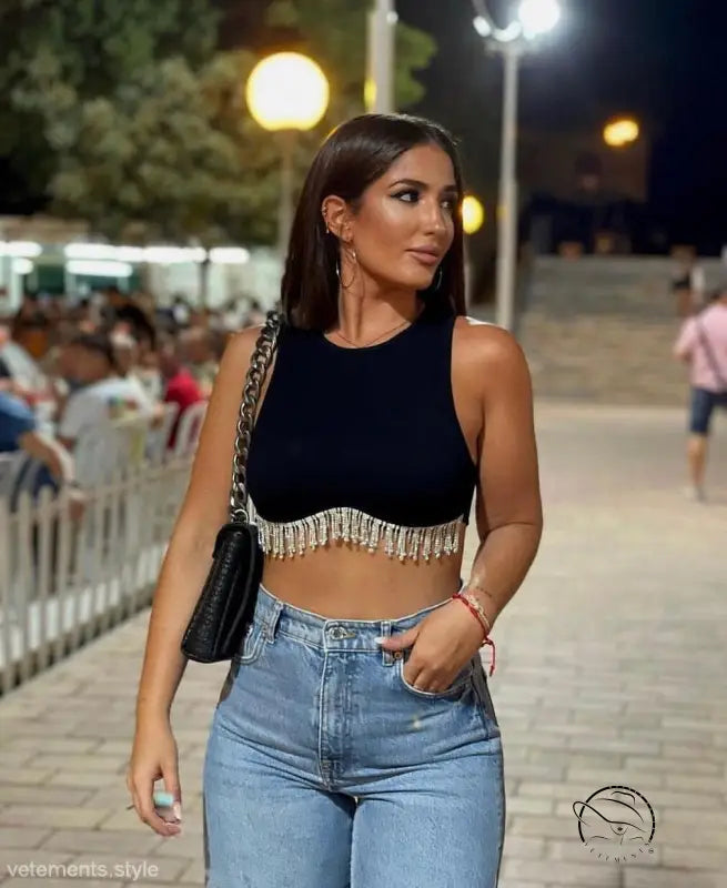 Woman in sexy daily vest: black fringe crop top with high-waisted jeans