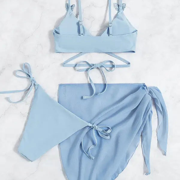 Light blue three-piece bikini set with a wrap skirt.