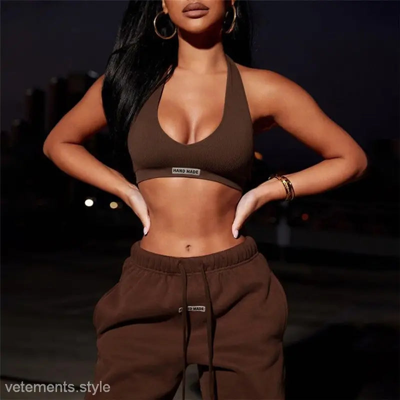 Woman in brown low-cut halter tight set with full-length pants and pockets posing confidently