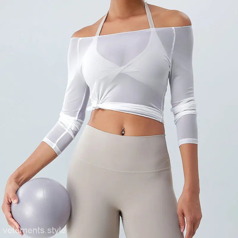 Woman wearing a sexy yoga blouse in coral red and light blue with leggings holding an exercise ball