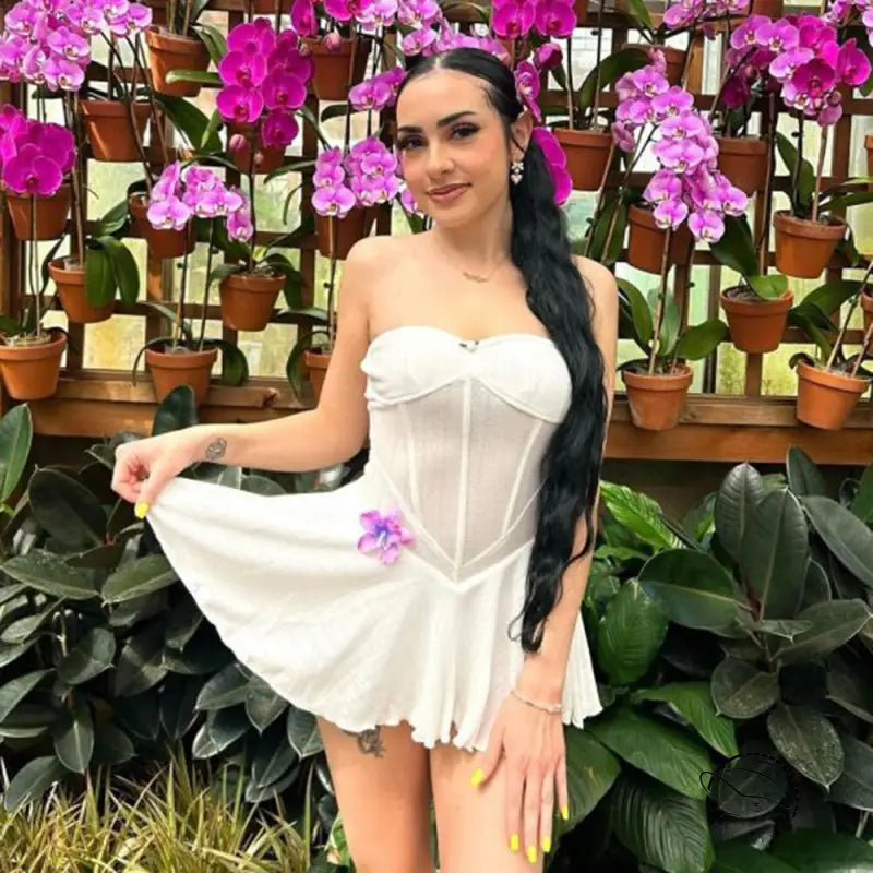 Woman in white strapless shoulder princess bodycon dress among orchids