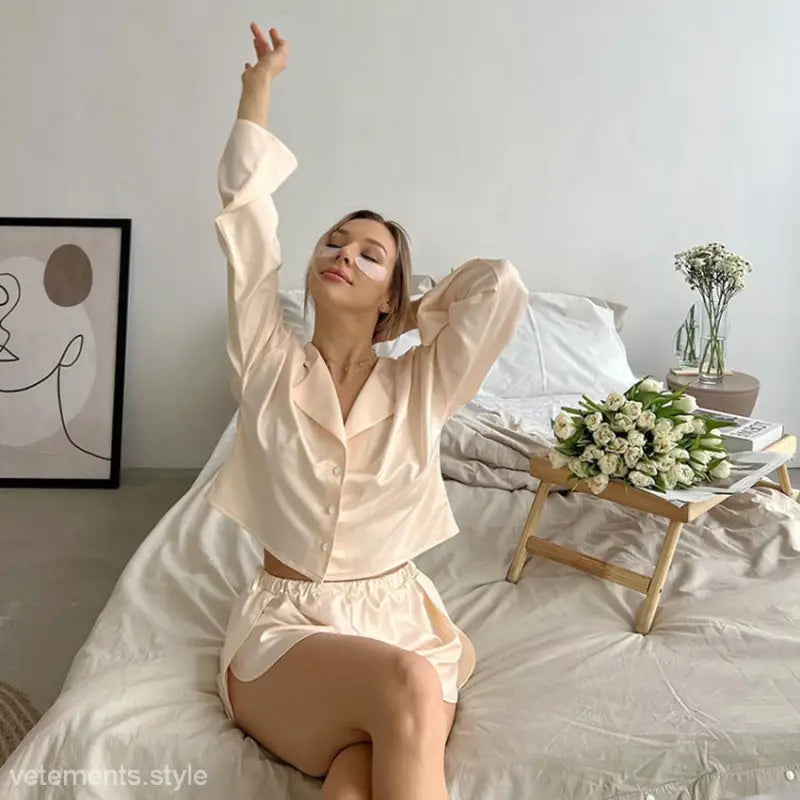 Woman in silk comfortable pajamas set featuring satin long sleeve top with button details