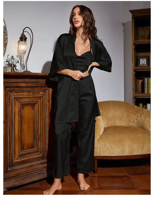 Woman in black silk home wear lounge set featuring a wide-legged jumpsuit and matching robe
