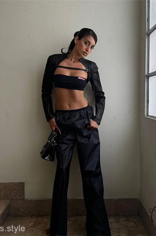 Woman in slim faux leather crop jacket, bandeau top, pants, handbag