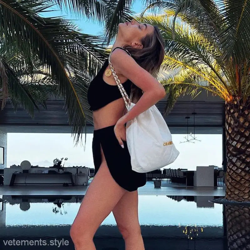 Woman in black casual vest and slit skirt set with white tote bag for summer fashion