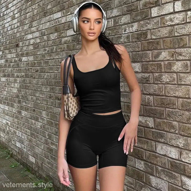 Woman in black athletic vest with headphones wearing slim shorts in summer shorts suit