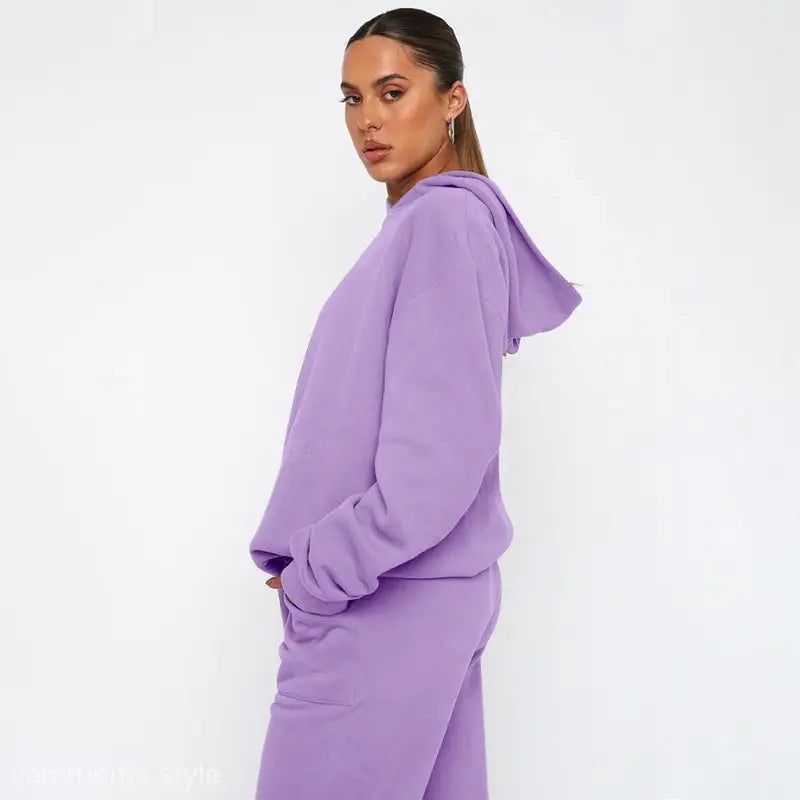 Woman wearing lavender hooded sweatshirt with long brown hair, soft touch trousers and long sleeve sweater