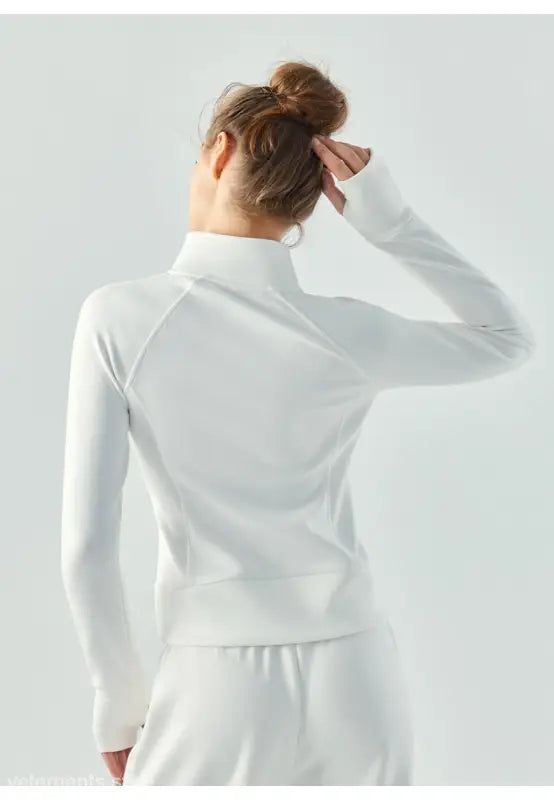 Woman wearing a white long-sleeved top with her hair in a bun, viewed from behind, showcasing the Sporty Air Layer Coat in Linen Green and Haiyan Ash for Spring/Fall