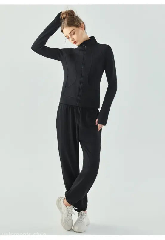 Woman in black athletic outfit with loose pants and white sneakers wearing linen green air layer coat