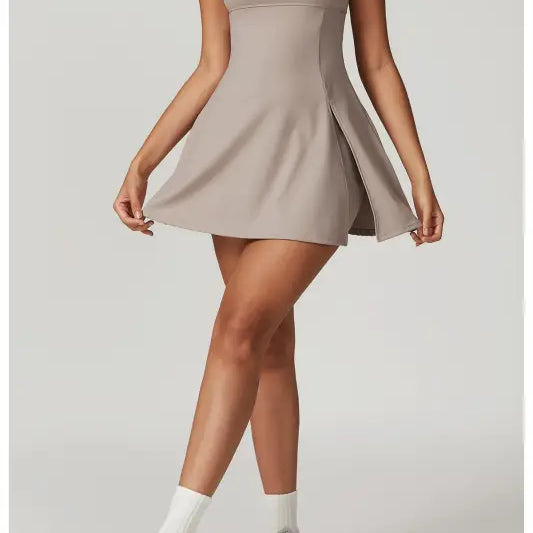 Beige spaghetti-strap mini dress with a flared skirt.