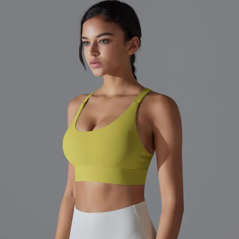 Yellow backless yoga vest with cutout and crossback design worn by a woman with dark hair