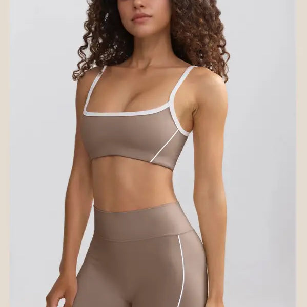 Woman wearing a taupe sports bra and matching high-waisted shorts with white trim.