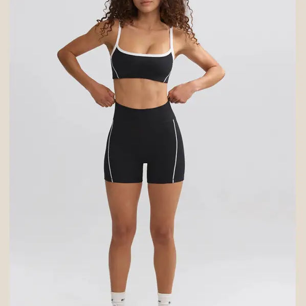 Woman with curly hair wearing black and white athletic workout attire and white sneakers.