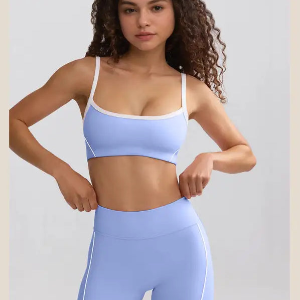 Young woman with curly hair wearing a light blue sports bra and matching shorts.