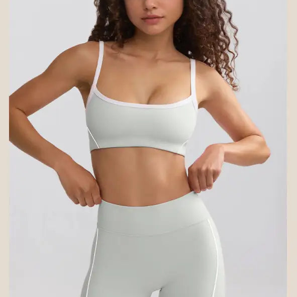 Young woman with curly hair wearing a white sports bra and matching high-waisted shorts.