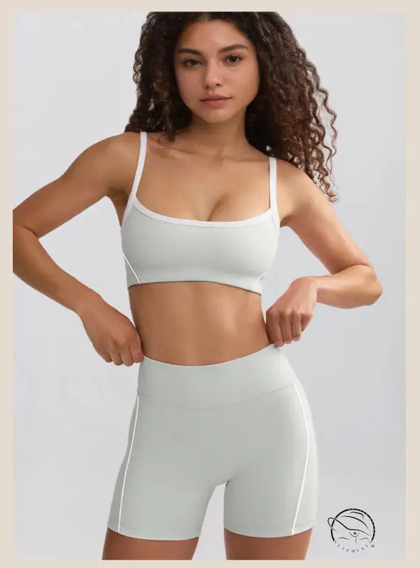 Young woman in curly hair wearing white sports bra and summer yoga clothes shorts