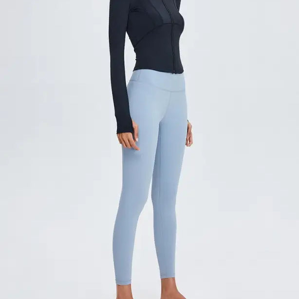 Woman wearing black long-sleeved top and blue leggings, showcasing Sporty Long Sleeve Nylon Tee in Phantom Black or Dark Gray Purple