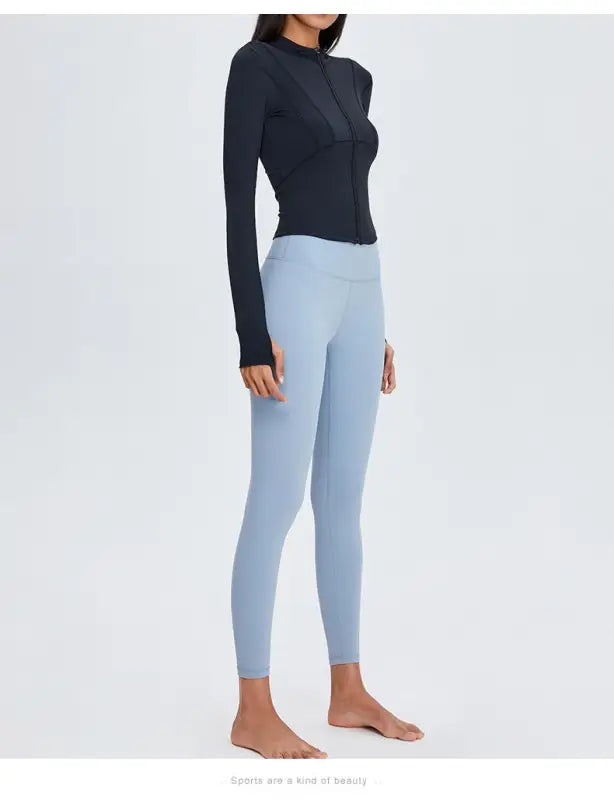 Woman wearing black long-sleeved top and blue leggings, showcasing Sporty Long Sleeve Nylon Tee in Phantom Black or Dark Gray Purple