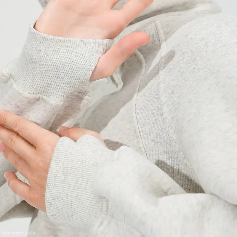 Hands in a light gray ribbed sweater with thumbholes, ideal for morning running warm workouts